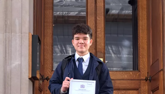 Young person holding a certificate standing on some steps