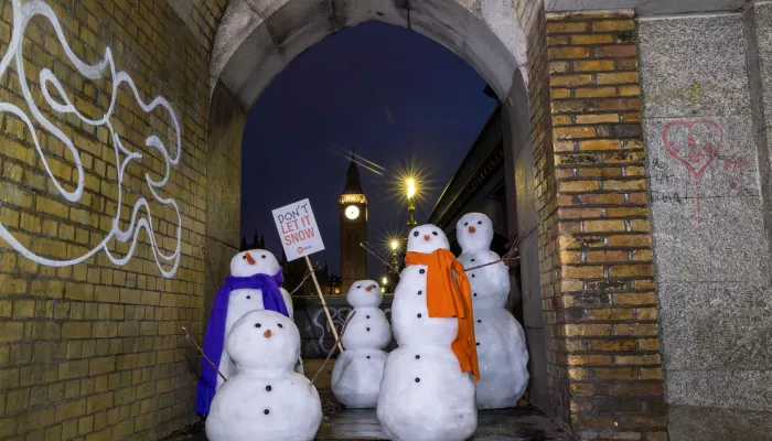 Snowmen outside the Houses of Parliament in London, with placards reading 'Don't Let It Snow'