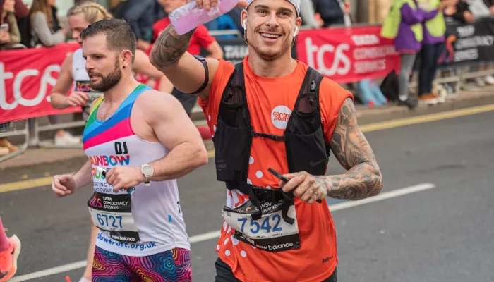 Runner waving at camera holding a water bottle
