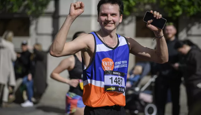 man in centrepoint vest running a marathon and cheering