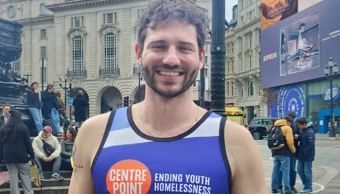 Alexander Lincoln in central London, wearing a Centrepoint running vest and smiling after the London Marathon