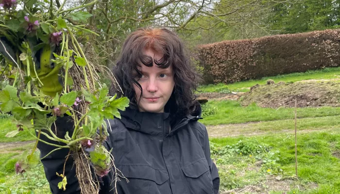 Young person holding up a bunch of weeds on a biodynamic farm