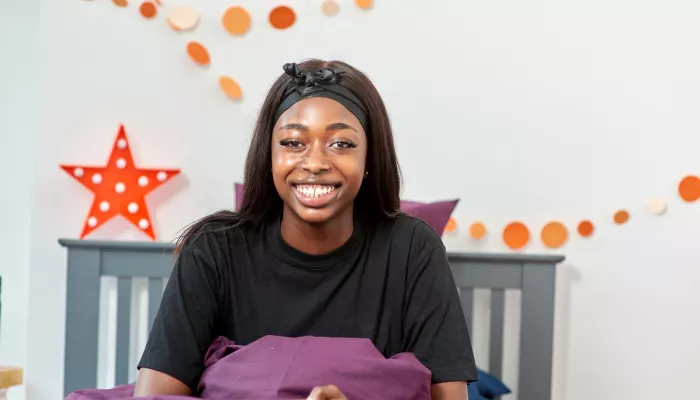 A young person sits in a cosy bed