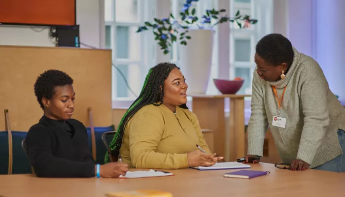 Young people sit in a classroom speaking to a teacher