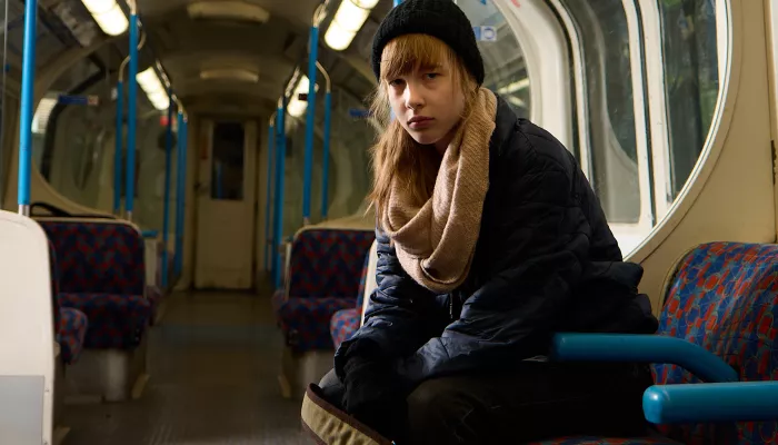 A young woman sits on a train, alone.