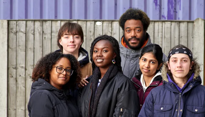 A group of young people affected by homelessness stand together and smile with hope