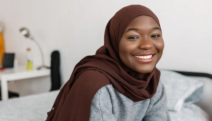 Young women smiling on her bed in her Centrepoint Room.