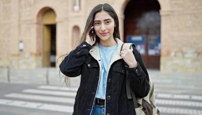 A young woman makes a phone call from the street.