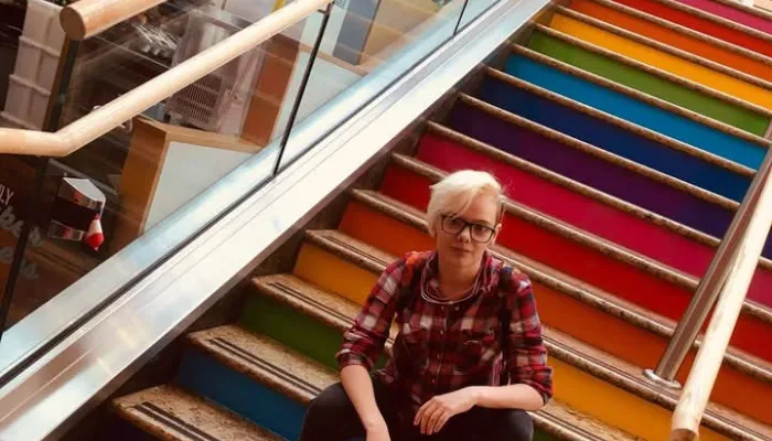 Young person sitting on rainbow stairs