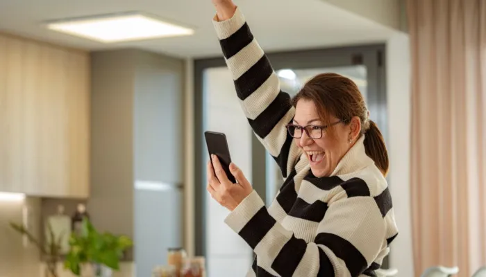 Image of lady celebrating whilst looking at her mobile phone