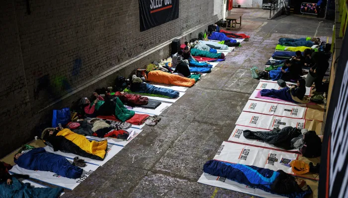 People at the Sleep Out lie on the floor in their sleeping bags