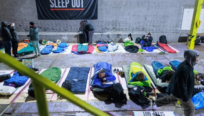 Participants at Manchester Sleep Out getting into sleeping bags 