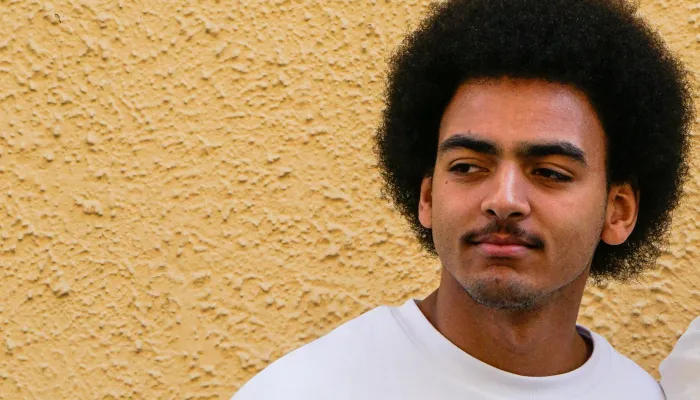 Young man standing in front of yellow wall