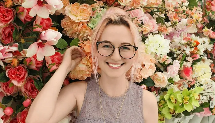Young woman smiling in front of a flower wall
