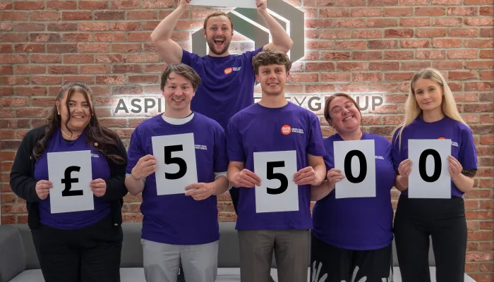 group of 6 corporate sleep out participants hold up their fundraising total: £5500