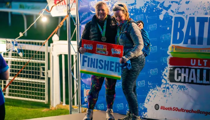 Two people holding a 'finisher' sign and smiling