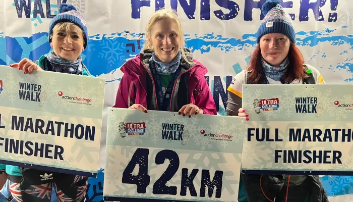 People at the finish line with signs showing they walked 42km