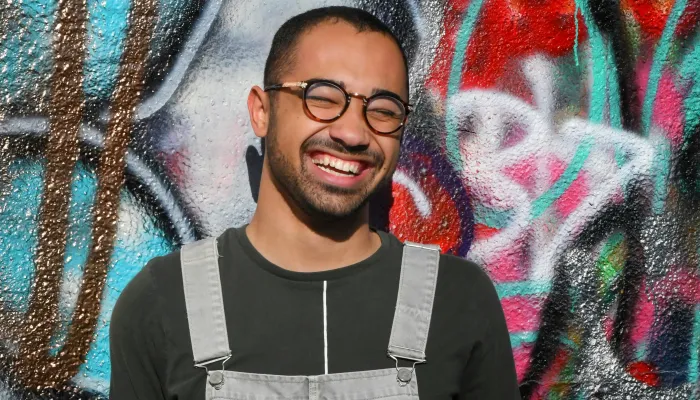 Young man smiling in front of a graffiti wall