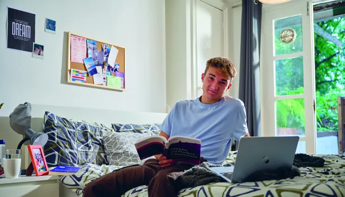 Young man sat on a bed smiling