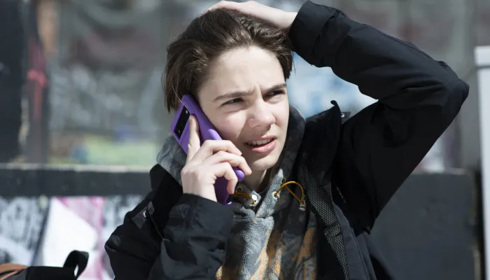 A young person in the street is on a call on their mobile phone