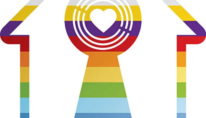 A house-shaped symbol with rainbow colours forming a keyhole in the centre and the  text "LGBTQ+ Housing Pioneer +" below it.