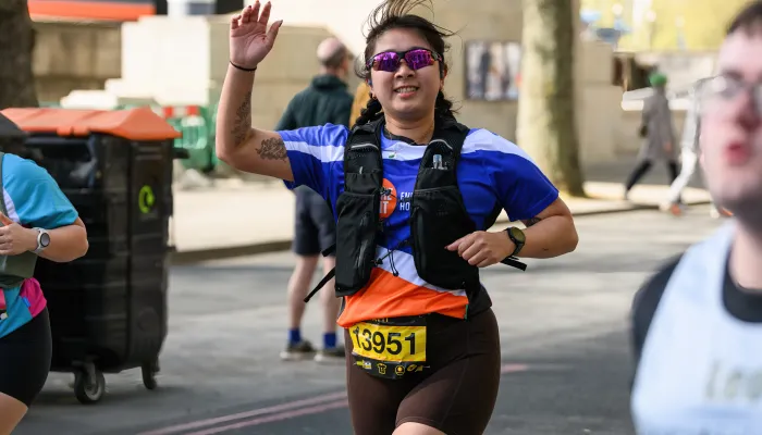 Image of a woman waving her hand as she runs past 