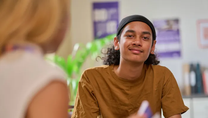 A young person smiles while chatting with a Centrepoint support worker