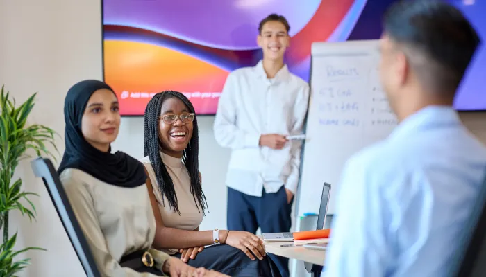 Smartly dressed young people laugh in an office meeting