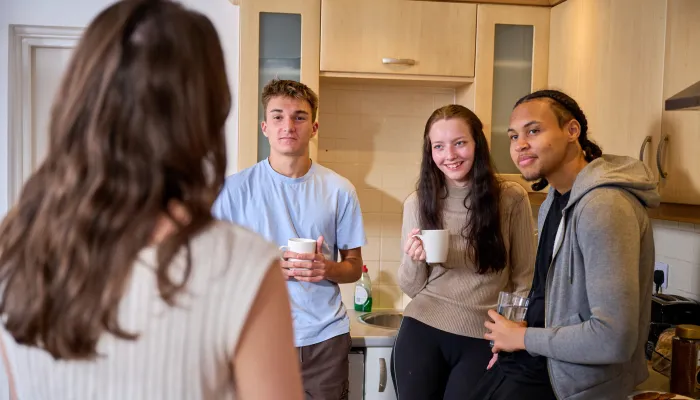 Young people chat in the kitchen of their shared home