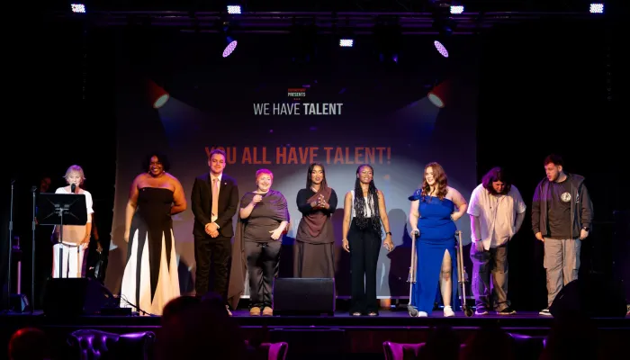 A group of young people stand in the spotlight on stage at Centrepoint Presents
