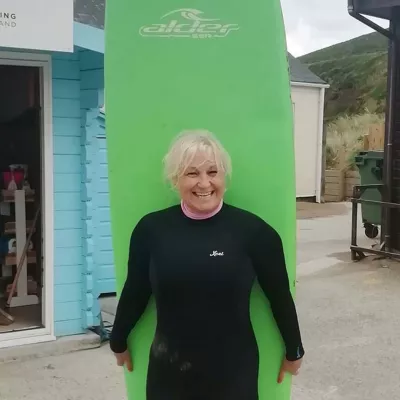 Person in wetsuit carrying surfboard