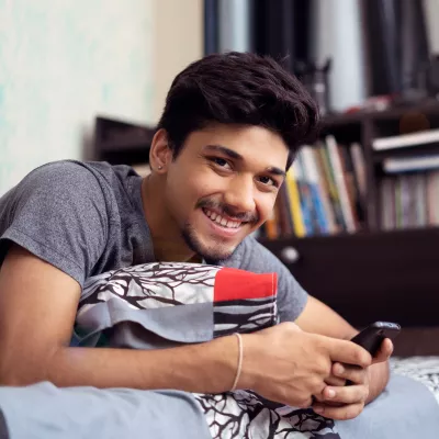 Young person smiling on bed in student halls