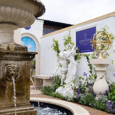 Photograph of a water fountain and statues at the Chelsea Flower Show with the Chilstone logo on a wall.
