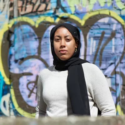 Young person stood against a wall with graffiti on 