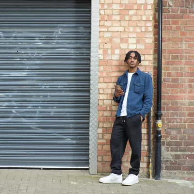 Young person outside near garage doors messaging on their mobile phone