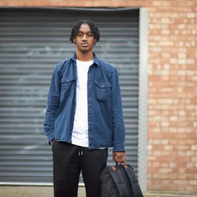A young person outside holding a rucksack