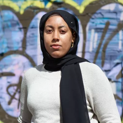 Young person stood against a wall with graffiti on 