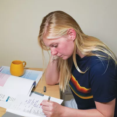 Young person with blond hair sitting at a desk studying