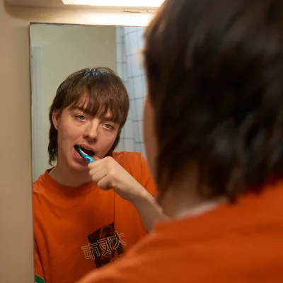 Young person looking into a mirror cleaning their teeth