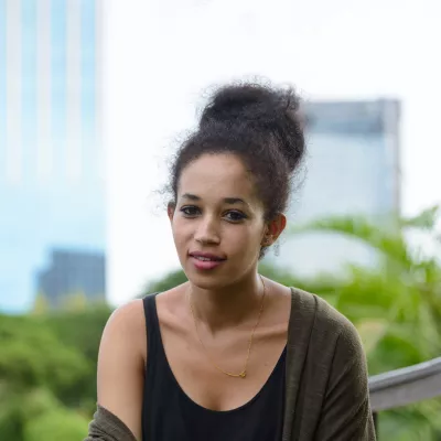 Young woman wearing a black vest sitting in a park