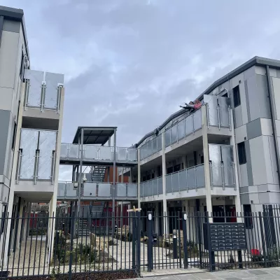 A block of new, affordable flats within a secure gated community. Each flat has its own front door and there is shared outside space in the middle of the block.