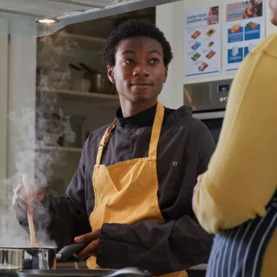 Young person wearing an apron and preparing food