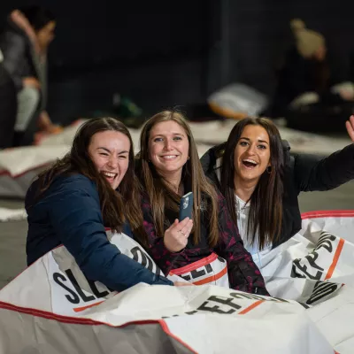 Three women smiling at the camera in Sleep Out branded sleeping bags