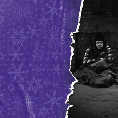 black and white image of Mia who is sat outside on the floor, with a sleeping bag, looking cold and homeless
