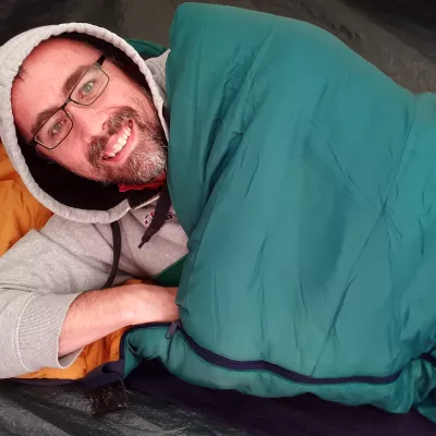 man lies in sleeping bag