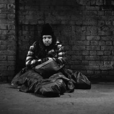 A black and white photo of Mia, sitting huddled in a sleeping bag in a dark street