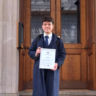 Young person holding a certificate standing on some steps