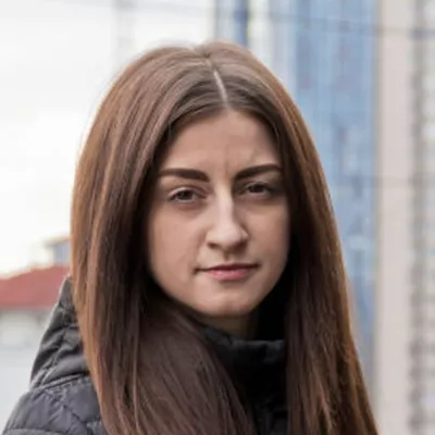 Young person standing in front of river and tall buildings