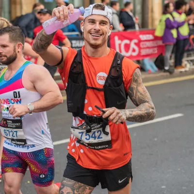 Runner waving at camera holding a water bottle