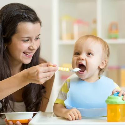 A mother feeds her baby with a spoon